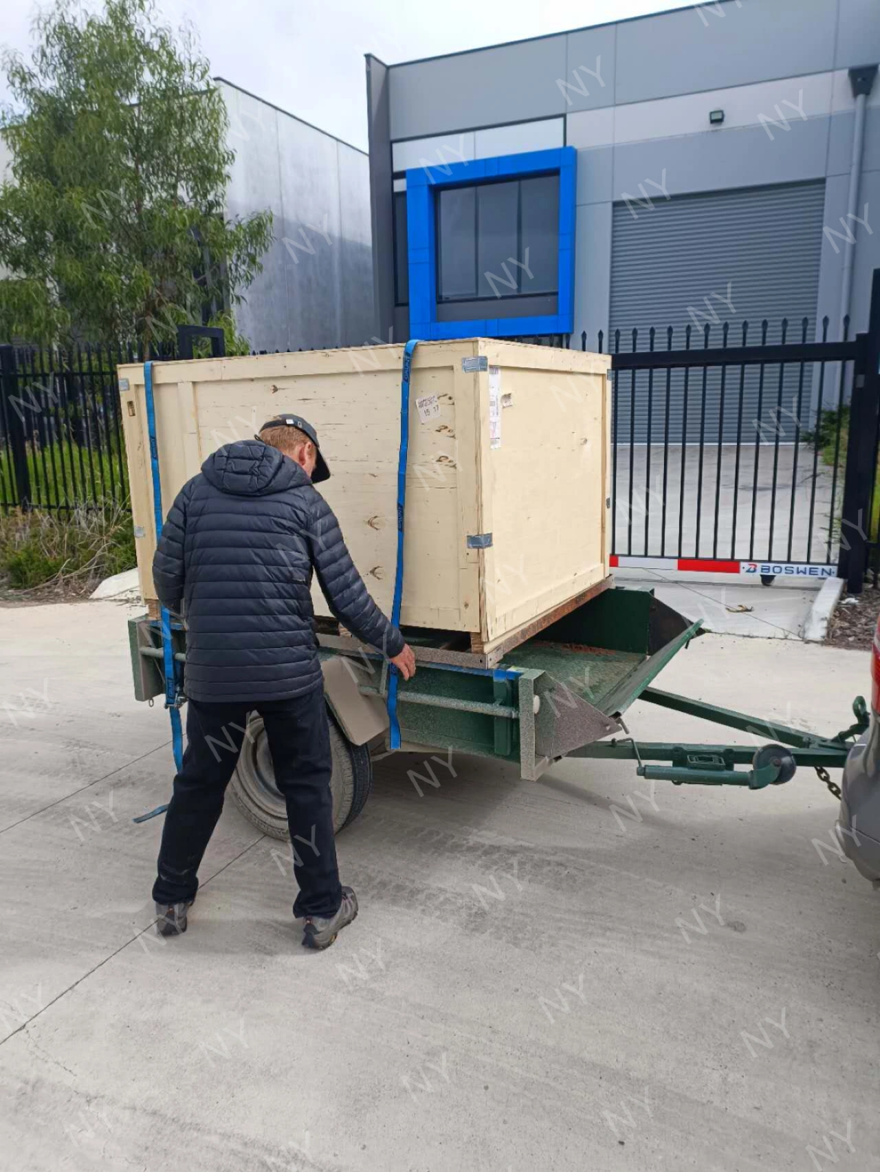Customer handling delivered wooden crate on local trailer
